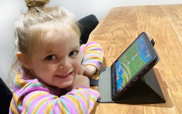 Three-year-old girl does Reading Eggs activity on iPad.