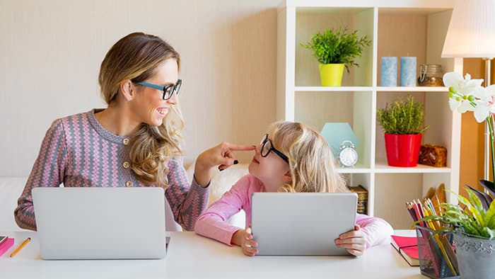 Four year old girl using online tutoring app with mother.